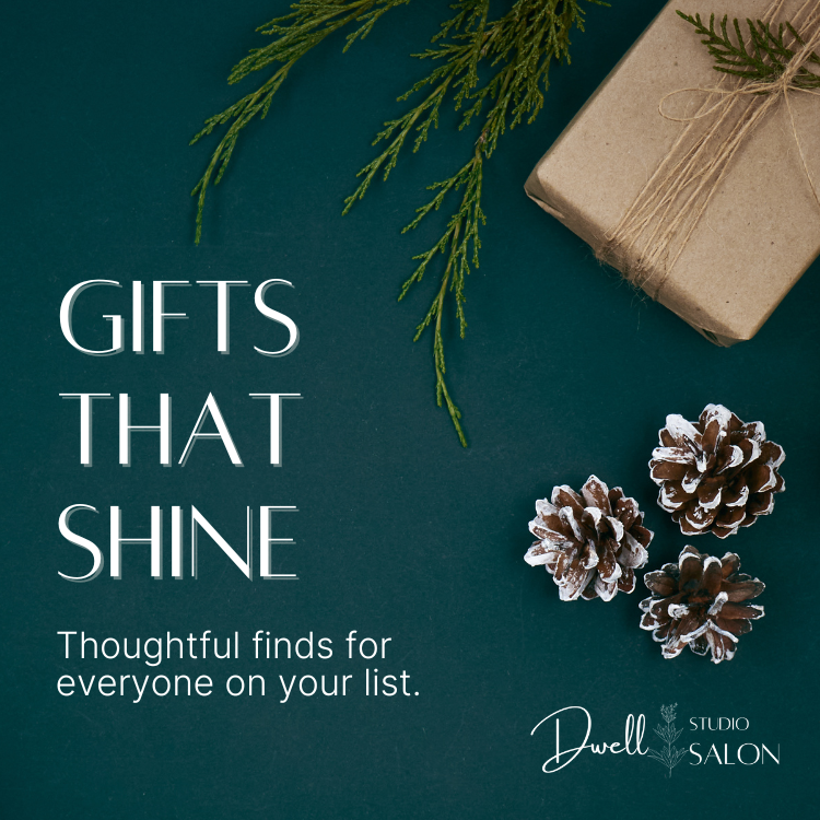 Flat-lay view of a pine-wrapped gift box, pinecones, and evergreen branches on a dark green background, with text reading "Gifts That Shine - Thoughtful finds for everyone on your list" by Dwell Studio Salon.