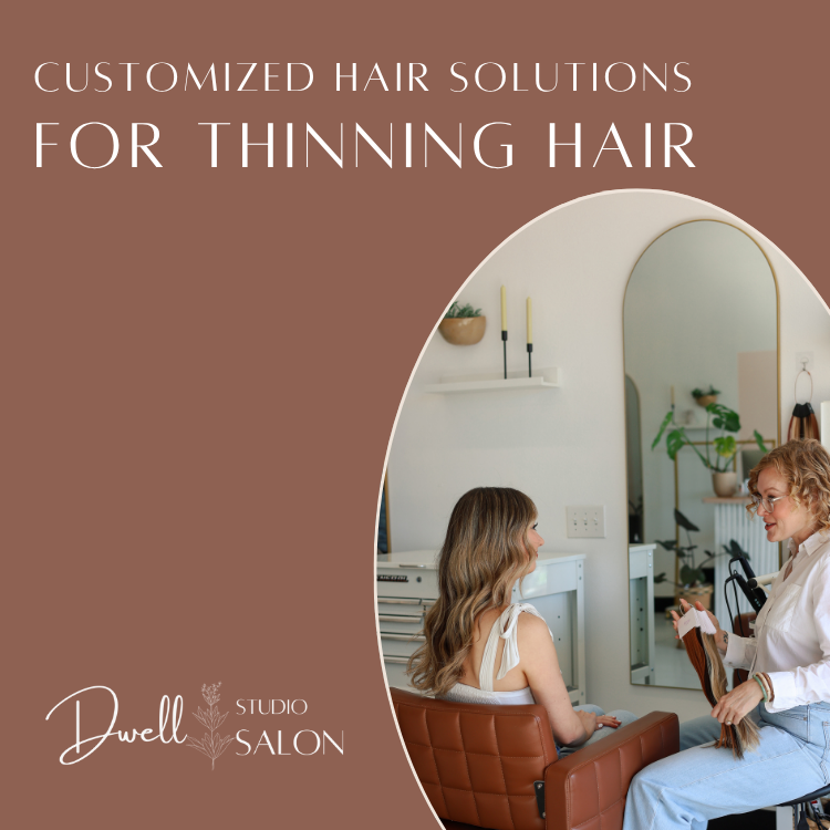 Hair stylist holding hair extension color swatches while consulting a client with long wavy hair sitting in a salon chair at Dwell Studio Salon.