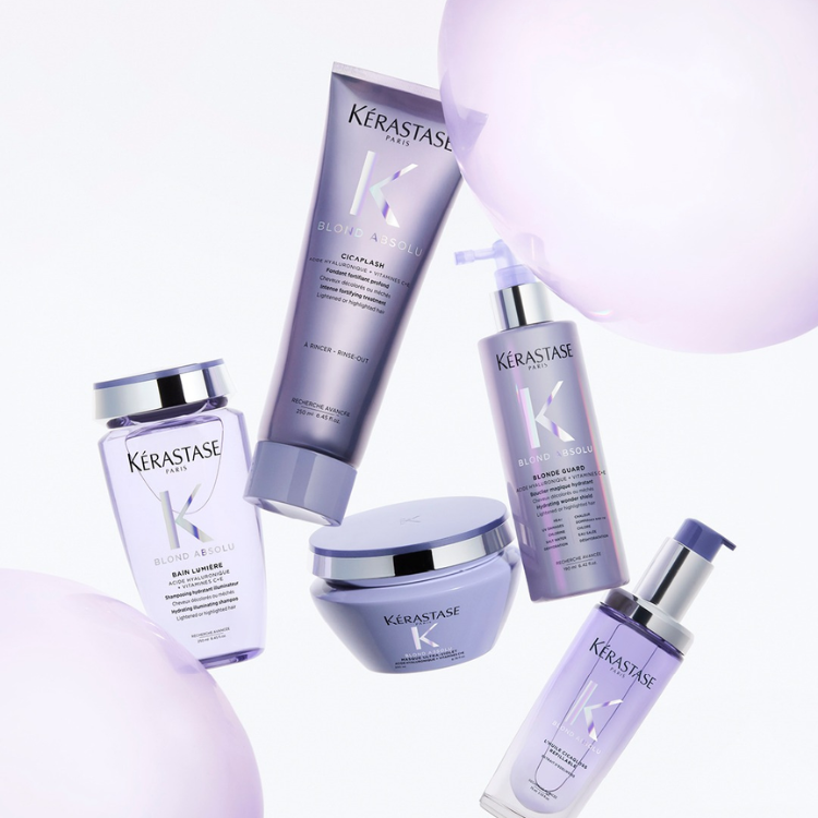 Floating collection of purple Kérastase Blond Absolu hair care products including shampoo, conditioner, and hair oil for blonde hair care