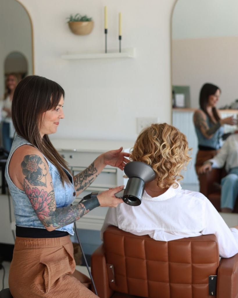 Ashley, curly hair expert, blow-drying a client's curls at Dwell Studio Salon in Fort Worth.