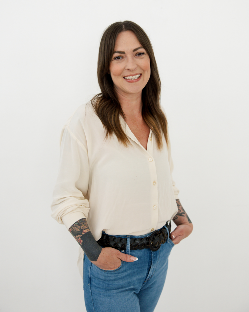 Stylist Ashley McRaney smiling in white shirt and jeans at Dwell Studio Salon in Fort Worth.