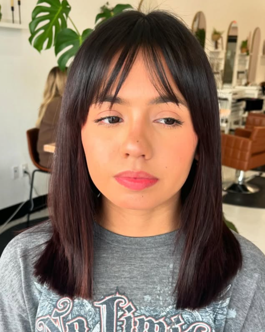 Portrait of a woman with a straight dark brown lob haircut and wispy sweeping bangs.