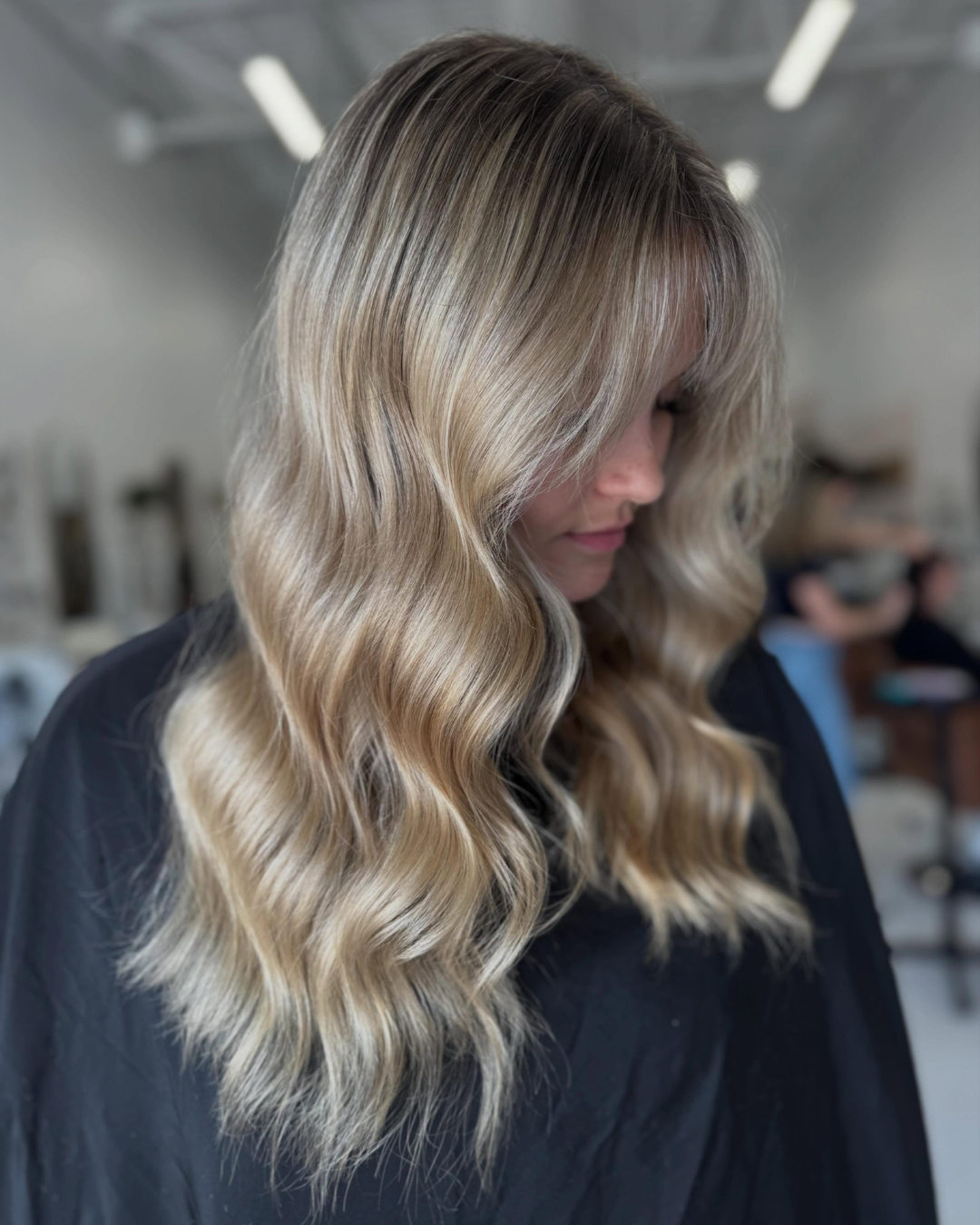 Side view of dimensional blonde hair with soft waves and face-framing layers.