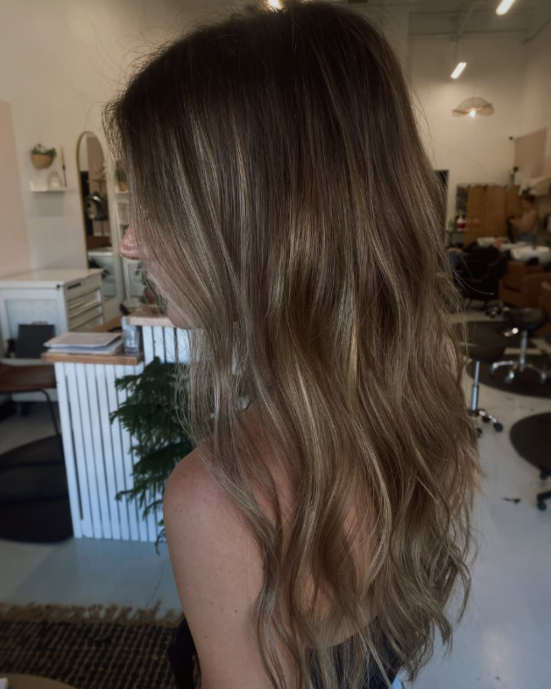 Side view of long, wavy bronde balayage hair with a seamless blend of brown and blonde tones.