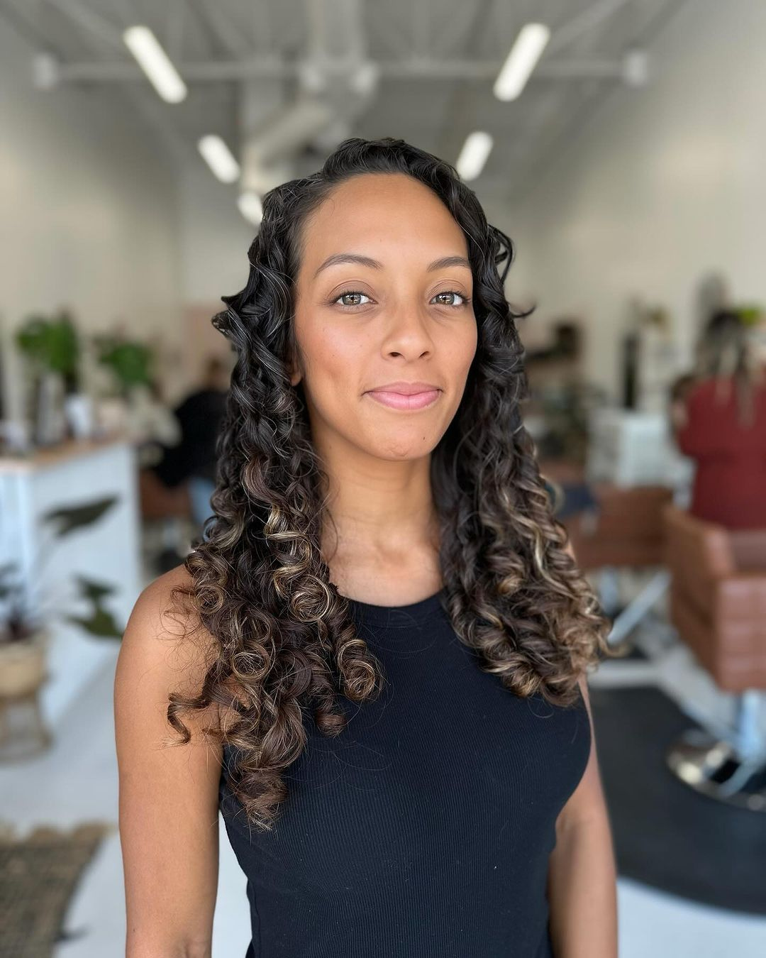 Client with defined coily hair smiling after a haircut in Fort Worth, Texas.