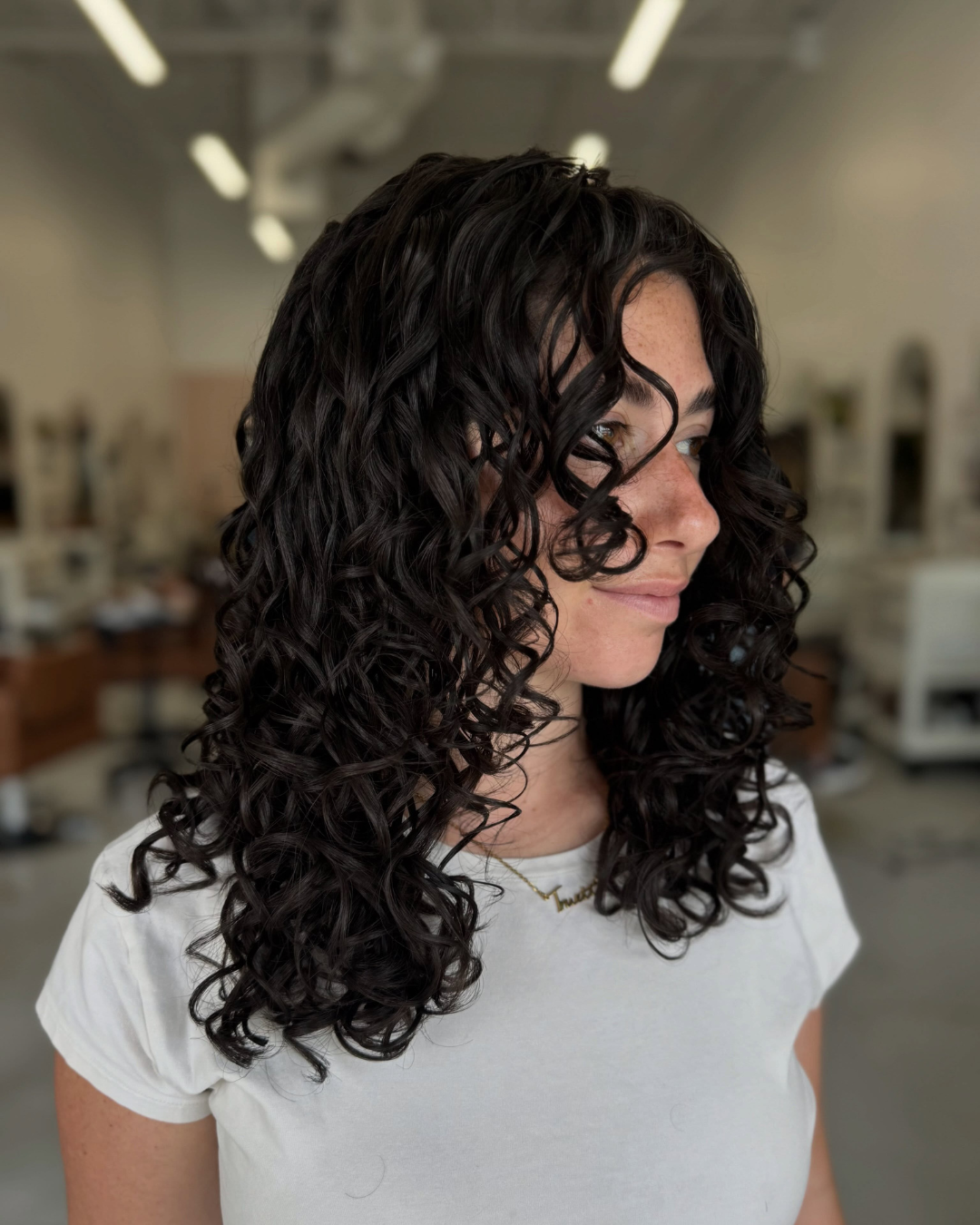 Side view of medium-length curly hair with brunette and blonde highlighted ringlets.