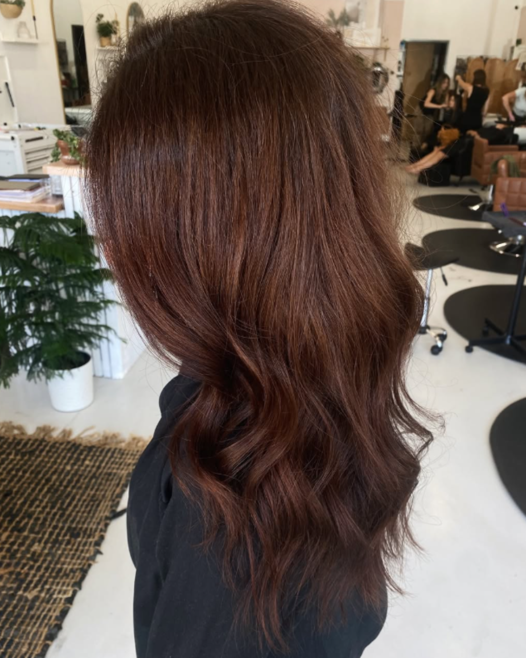 Side profile of long, rich dark brown hair with custom warm undertones styled in soft waves.