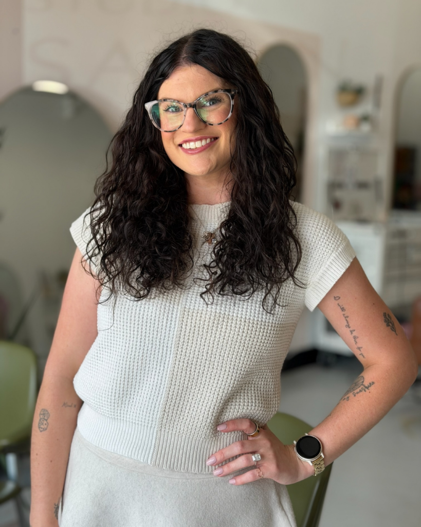 Hair stylist Danielle Mitcham with curly dark hair and glasses.