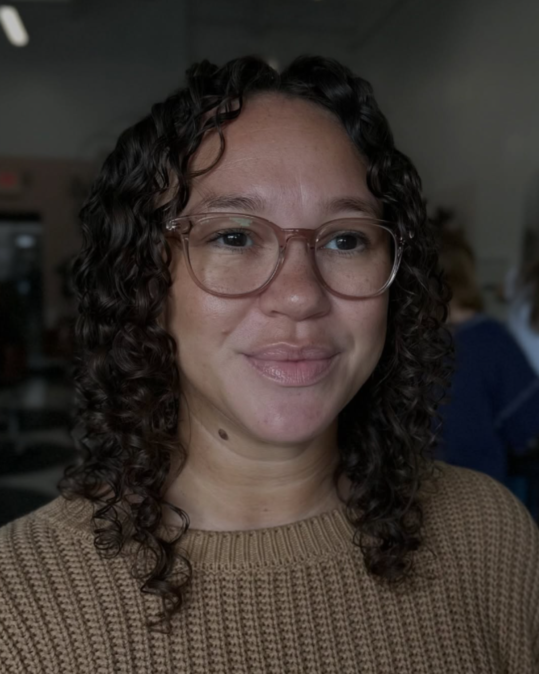 Woman with long, dry-cut natural gray and silver curly hair posing for a portrait by Angela.
