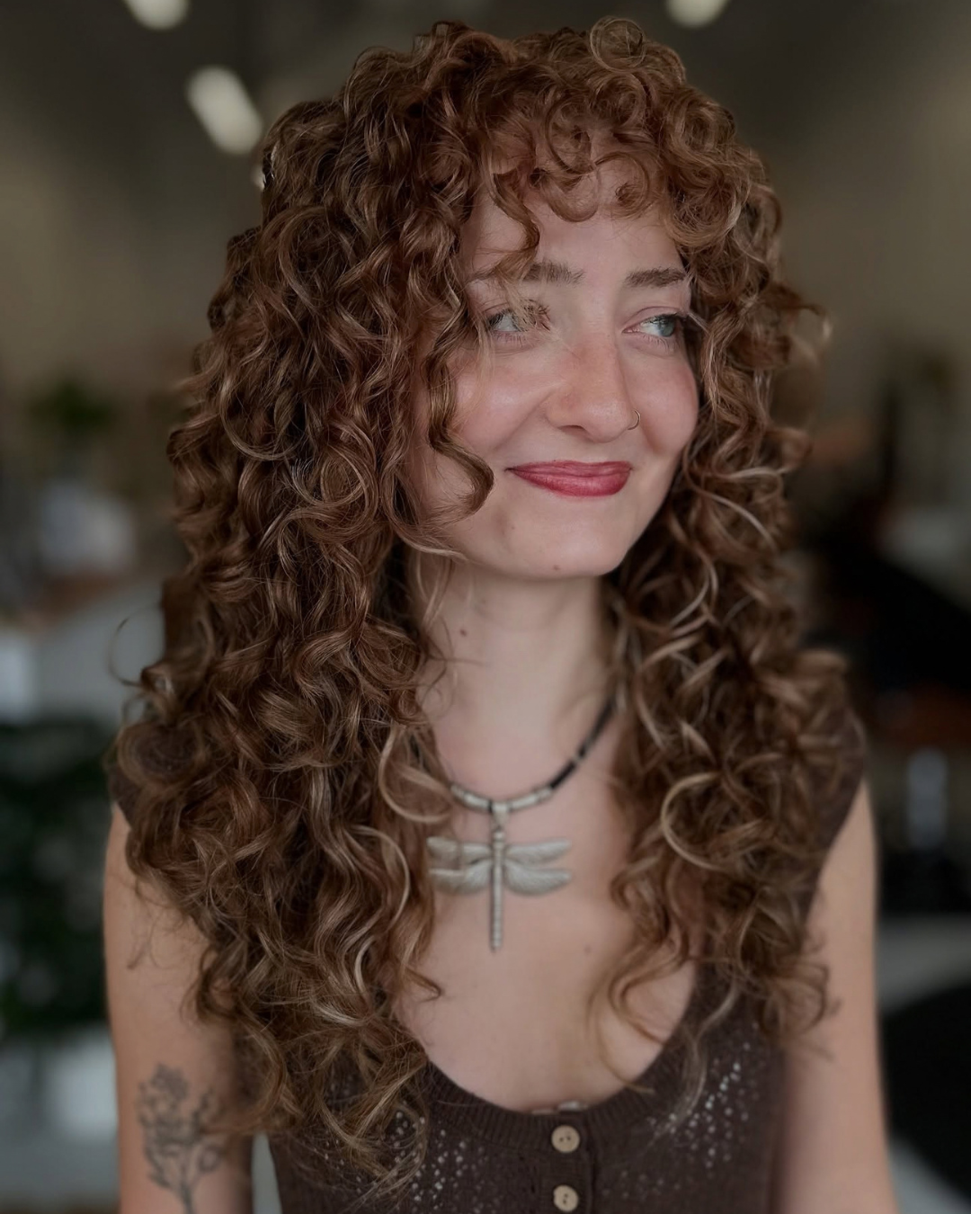 Side profile of a woman showing off long, layered gray curly hair styled with definition.