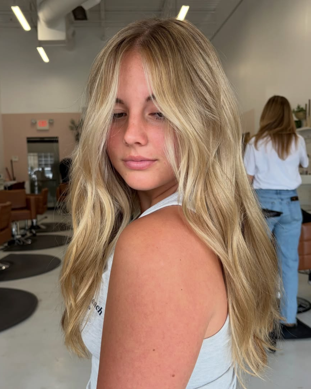 Woman with long lived-in blonde hair and face-framing highlights by Abigail.