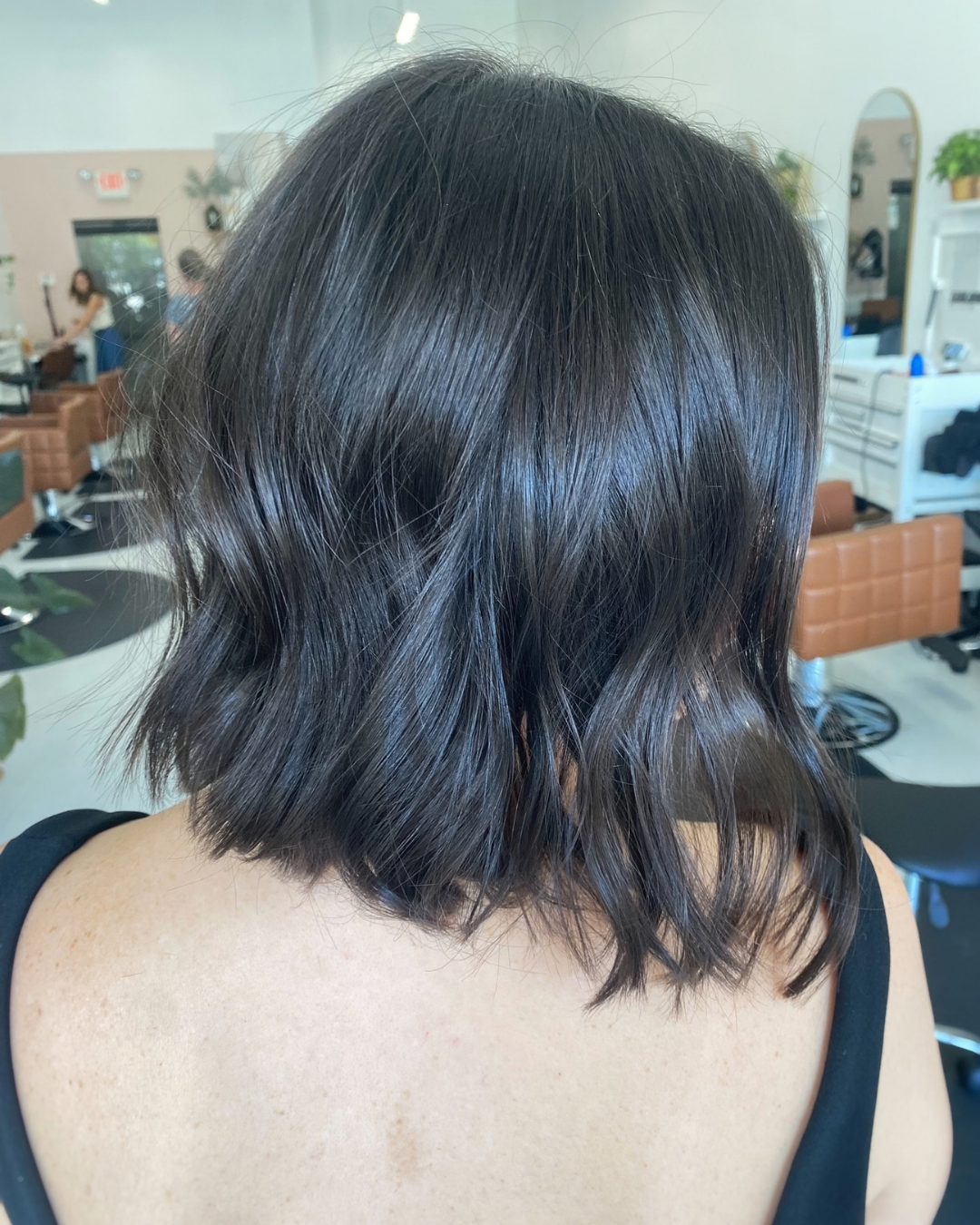 Back view of a short, dark brown textured bob haircut with soft, effortless waves.